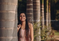 a young woman leaning against a tree