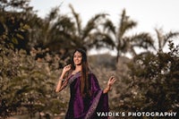 a woman in a purple sari standing in a field