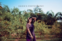 a woman in a purple sari posing in an orange field